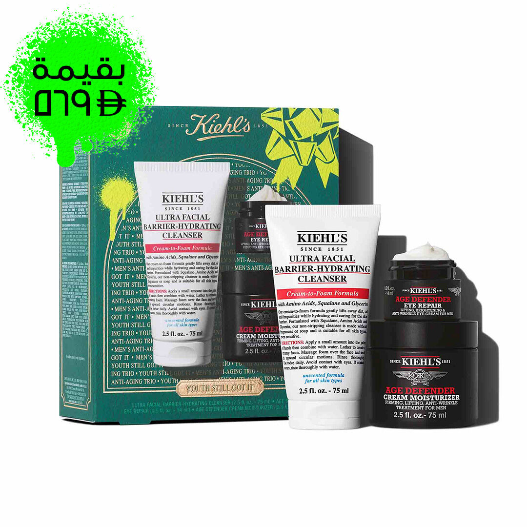 A graphic featuring a dark teal Kiehl’s gift box with white and gold accents on the left. The box contains three products. To the right of the box, the same three products are displayed outside of the box: a white tube of "KIEHL’S ULTRA FACIAL BARRIER-HYDRATING CLEANSER," a small black and red jar of "KIEHL’S AGE DEFENDER EYE REPAIR," and a larger black and red jar of "KIEHL’S AGE DEFENDER CREAM MOISTURIZER." The box is decorated with bright green graphic paint splatters and a bow design and features the text "YOUTH STILL GOT IT" at the bottom.
