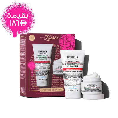 A graphic displaying a white "KIEHL'S ULTRA FACIAL BARRIER-HYDRATING CLEANSER" tube labeled "FULL SIZE" and a smaller white "KIEHL'S ULTRA FACIAL CREAM" jar labeled "TRAVEL SIZE". In the upper right, a pink splattered text box reads "VALUE $40". A partial Kiehl's gift box with a pink graphic bow is visible in the bottom right corner.